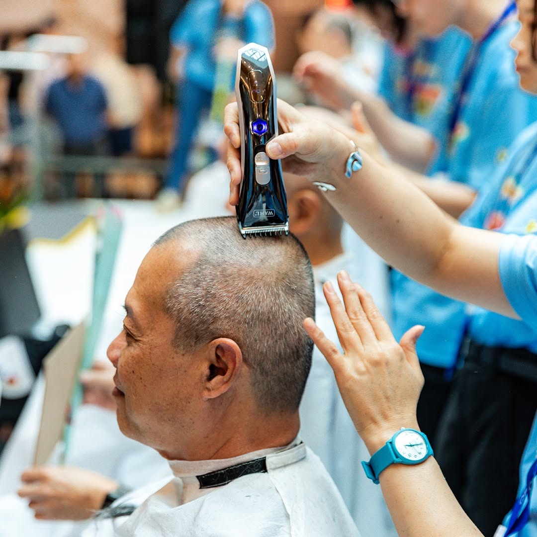 A stylist shaving a participant's head during Hair for Hope