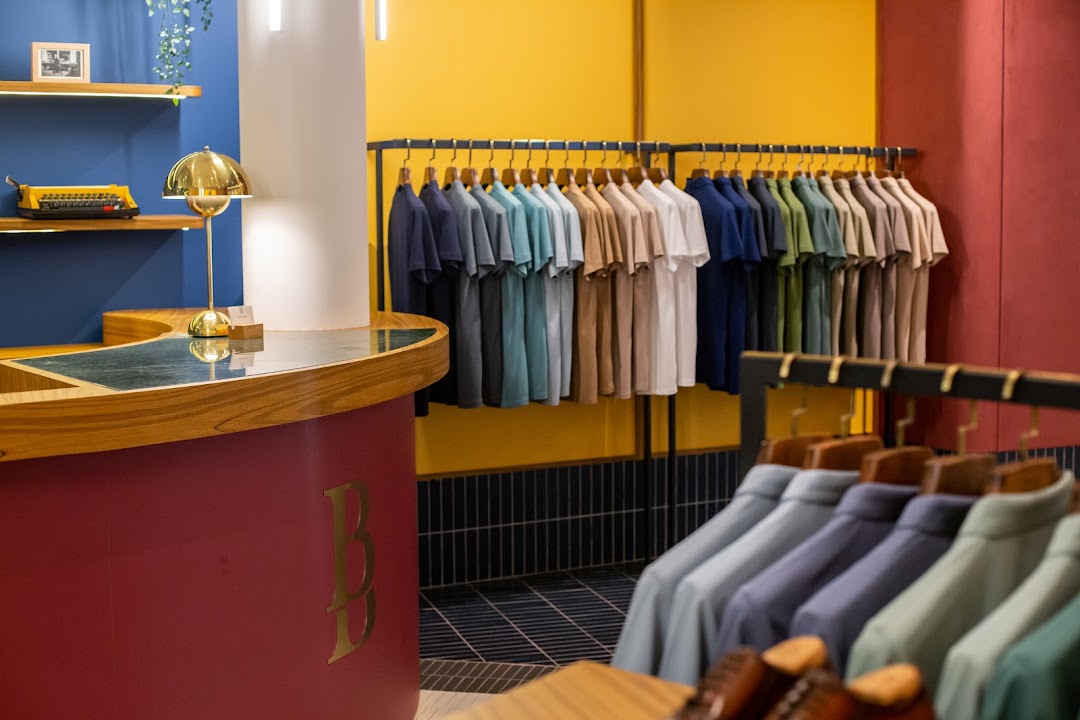 Interior of a clothing store with racks of colorful polo shirts and a checkout counter.
