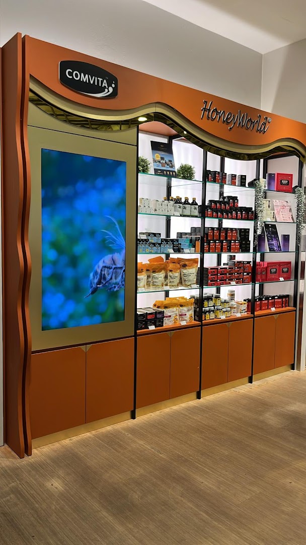 A well-lit retail display featuring Comvita and HoneyWorld products, with a digital screen showcasing nature.