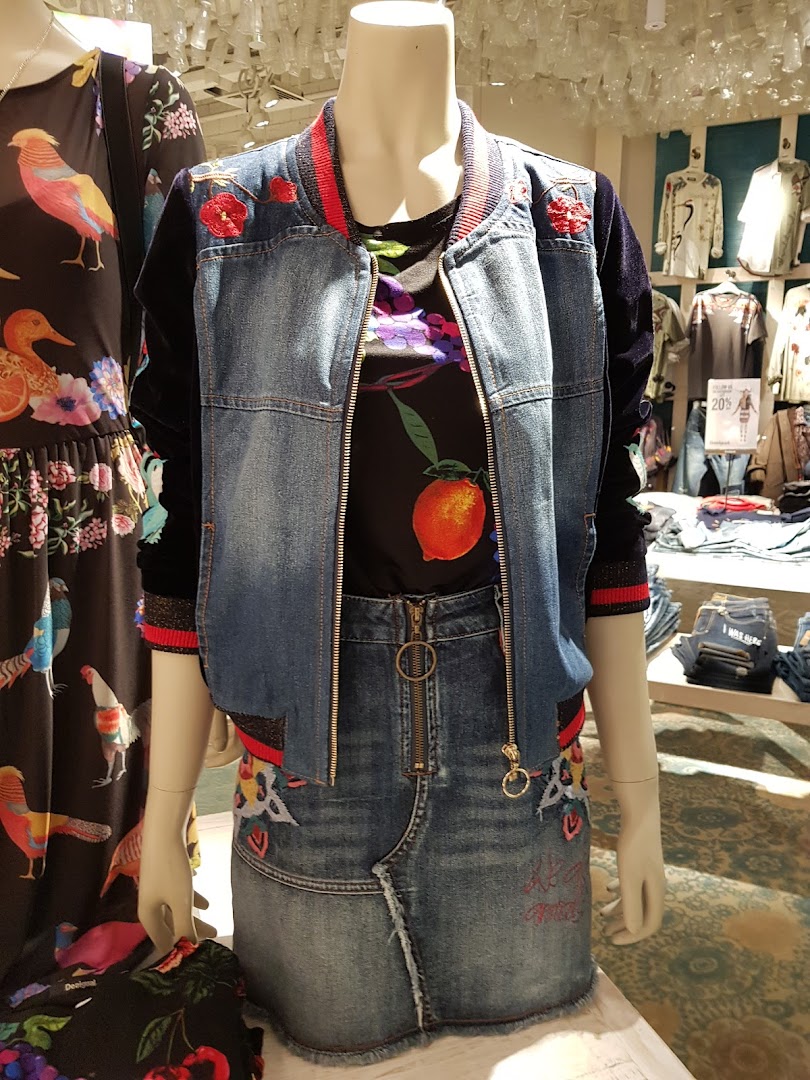Mannequins display colorful denim outfits with embroidered details and vibrant prints.