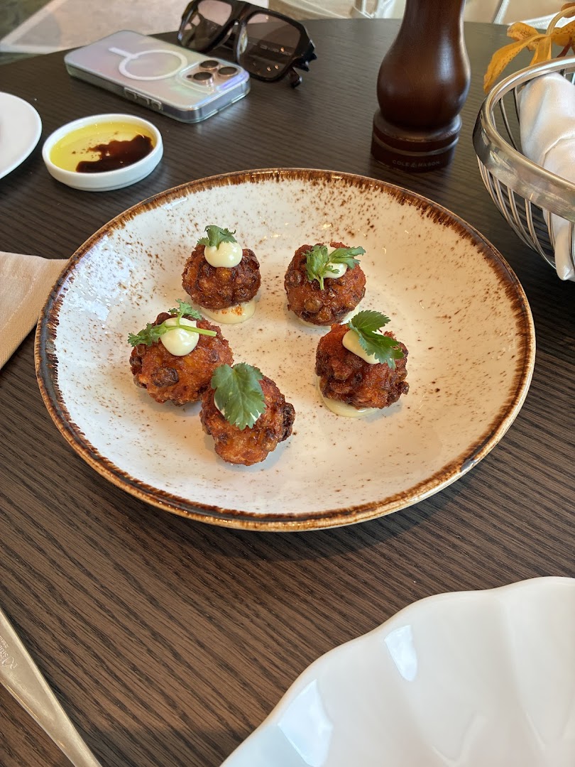 A plate of five appetizers with a dipping sauce and a basket of bread.