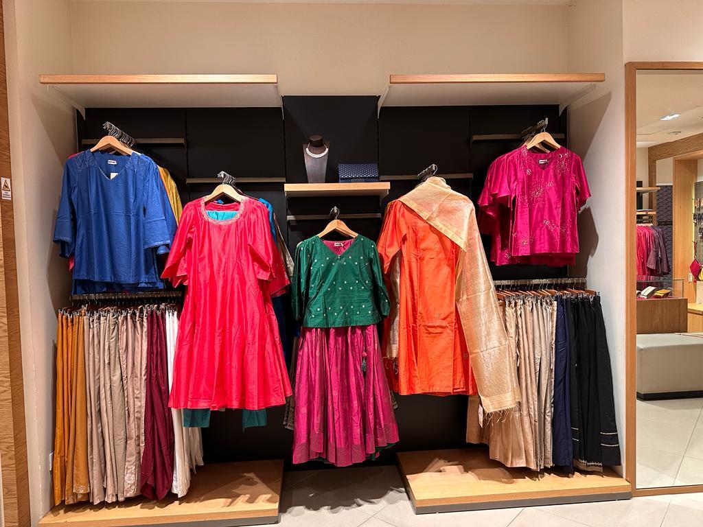 A display of colorful Indian ethnic wear for women, including kurtis and skirts.