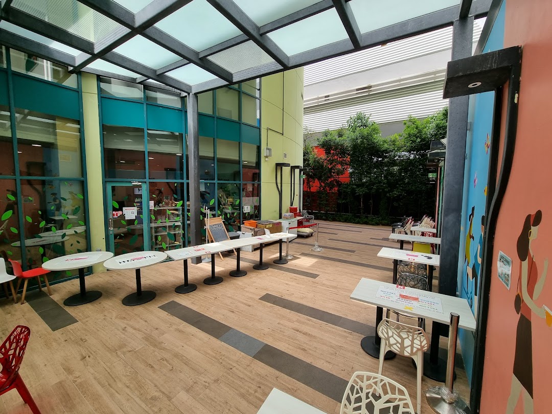 An outdoor seating area with tables and chairs under a covered walkway.
