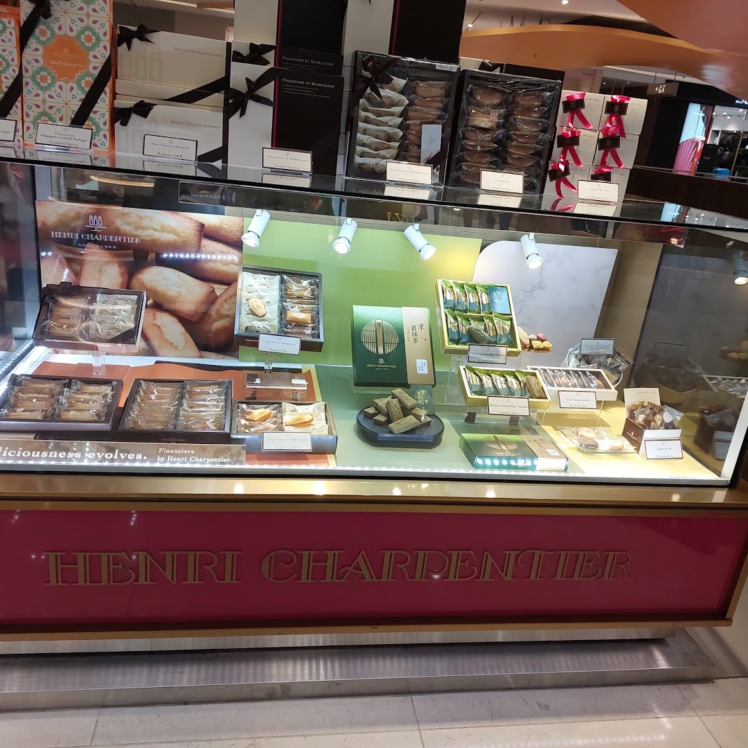 A display case filled with assorted pastries and gift boxes from Henri Charpentier.