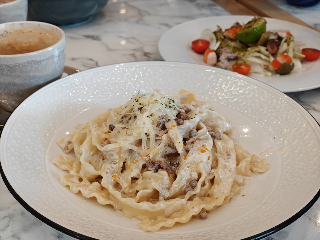A close-up of a creamy pasta dish with grated cheese and a side salad with octopus.