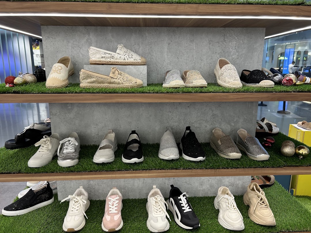 A display of various stylish women's shoes on shelves, including espadrilles, sneakers, and flats.