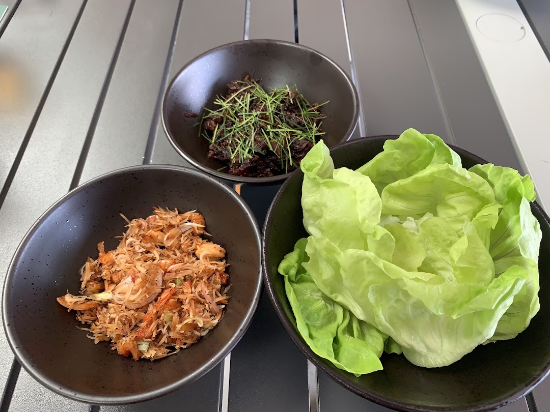 Three bowls of food are displayed on a table: lettuce, shredded meat, and a savory dish with herbs.