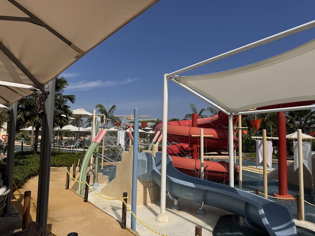 A water park with slides, splash features, and shaded seating areas under a clear blue sky.