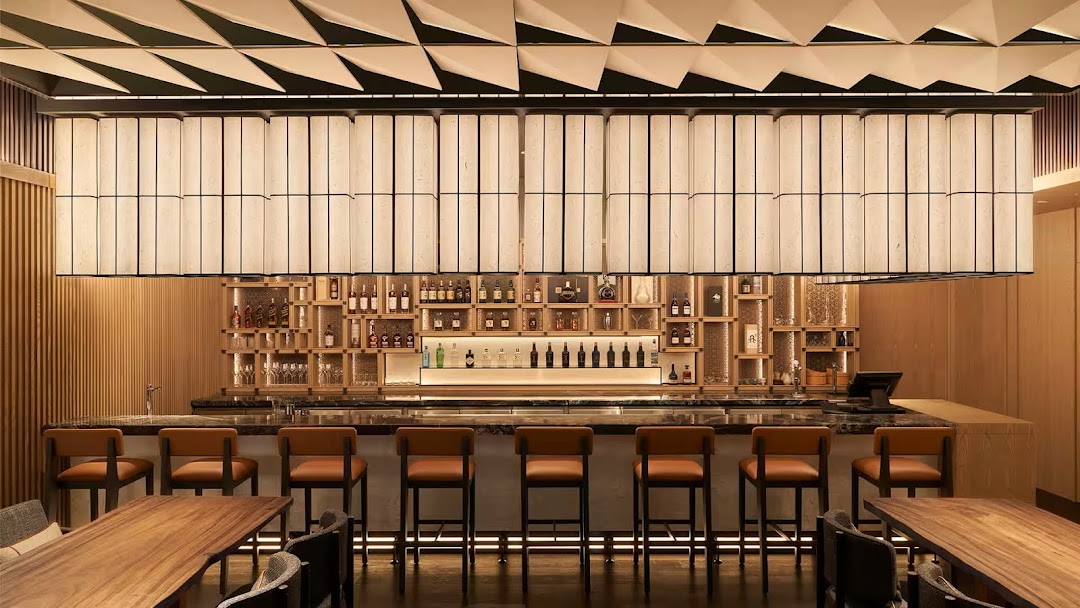 Interior shot of a modern bar with a well-stocked liquor shelf and seating.