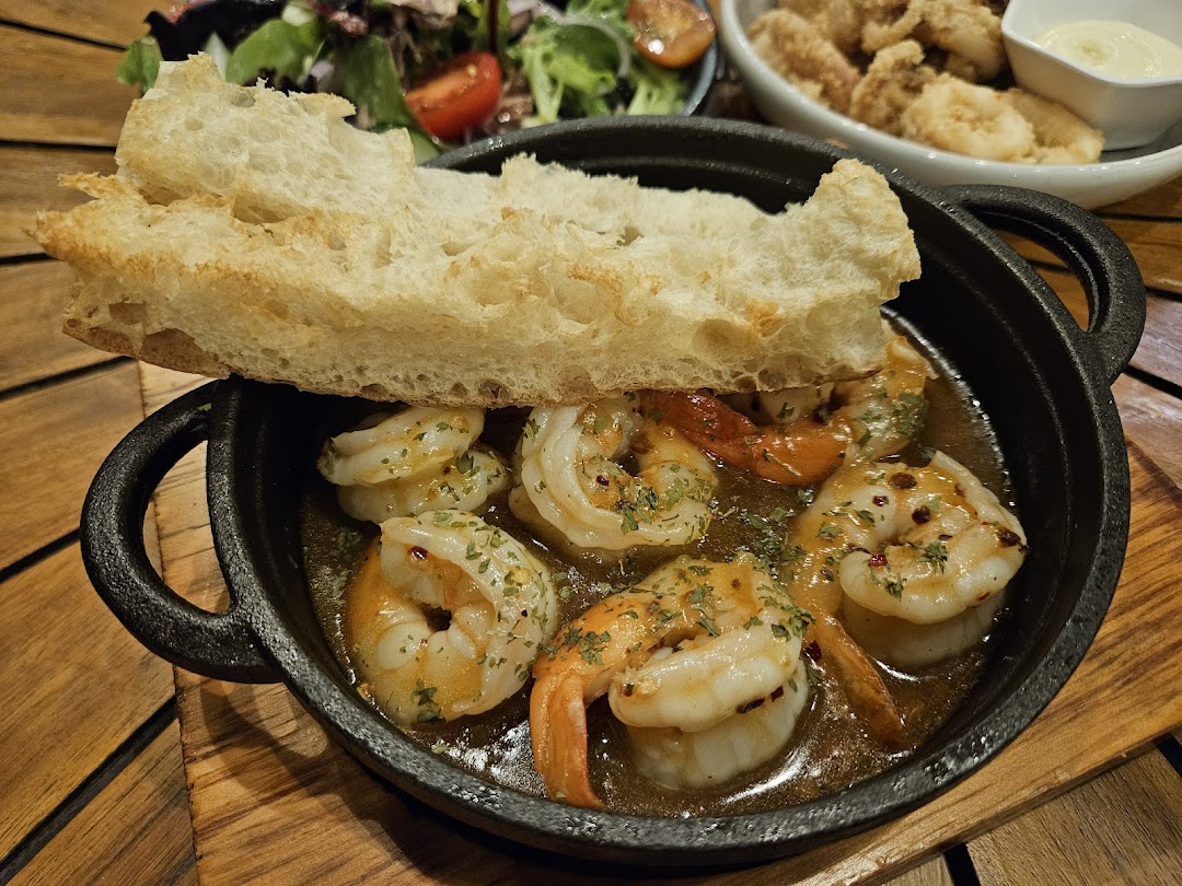 A close-up of a sizzling garlic shrimp dish with a piece of bread on top.