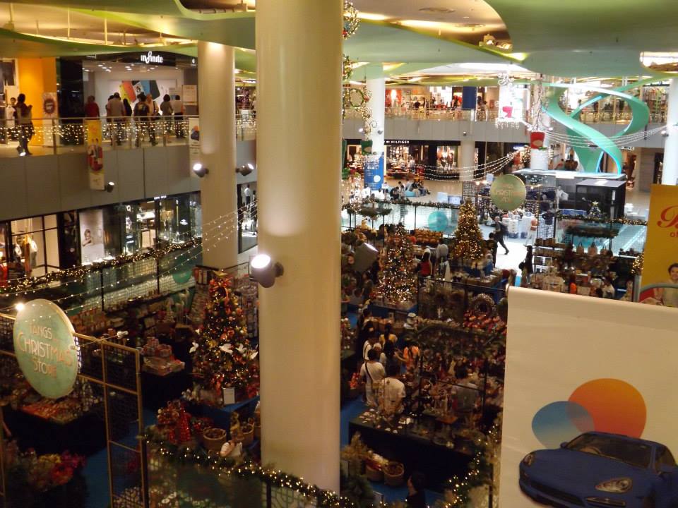 A bustling shopping mall interior with Christmas decorations and shoppers.